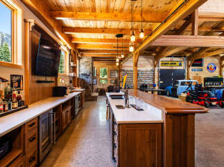 Experience the ultimate man cave with this stunning custom-built bar and entertainment area, featuring a fully stocked bar, multiple refrigerators, and a large television.