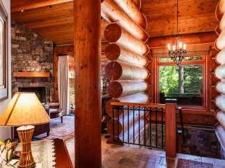 Experience rustic charm in this stunning log cabin home, featuring a grand stone fireplace and a warm, inviting atmosphere.
