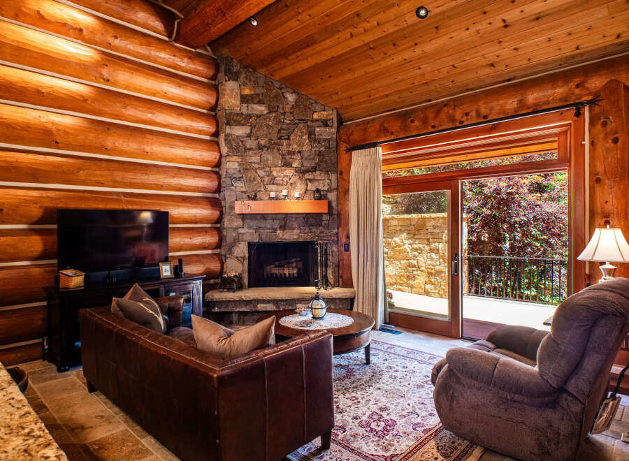 Experience rustic charm in this cozy log cabin living room, featuring a grand stone fireplace perfect for chilly evenings.