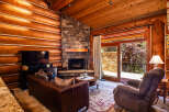 Experience rustic charm in this cozy log cabin living room, featuring a grand stone fireplace perfect for chilly evenings.