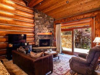 Experience rustic charm in this cozy log cabin living room, featuring a grand stone fireplace perfect for chilly evenings.