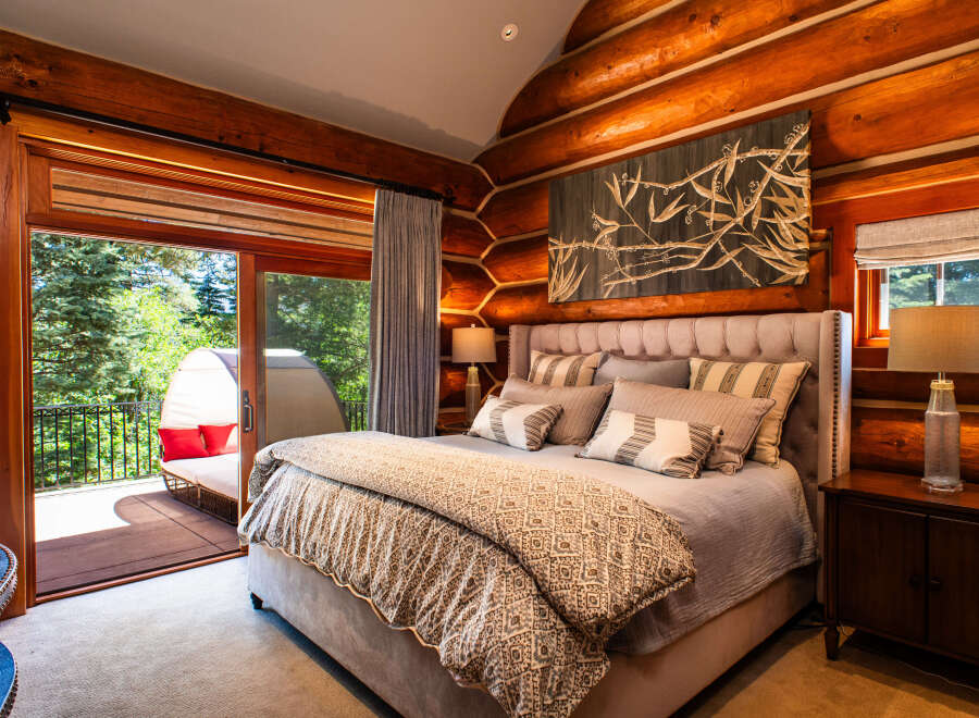 Experience rustic luxury in this stunning log cabin bedroom, featuring a plush king-sized bed adorned with decorative pillows and a cozy comforter.
