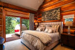 Experience rustic luxury in this stunning log cabin bedroom, featuring a plush king-sized bed adorned with decorative pillows and a cozy comforter.