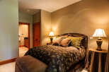 This inviting bedroom features a plush queen-sized bed adorned with a rich paisley comforter and decorative pillows, creating a cozy and luxurious retreat.