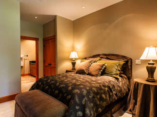 This inviting bedroom features a plush queen-sized bed adorned with a rich paisley comforter and decorative pillows, creating a cozy and luxurious retreat.