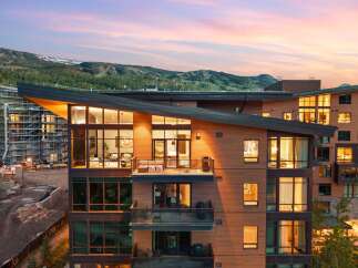Experience luxury mountain living in this stunning modern residence, featuring expansive floor-to-ceiling windows that showcase breathtaking panoramic views of the surrounding peaks and vibrant sunset skies.