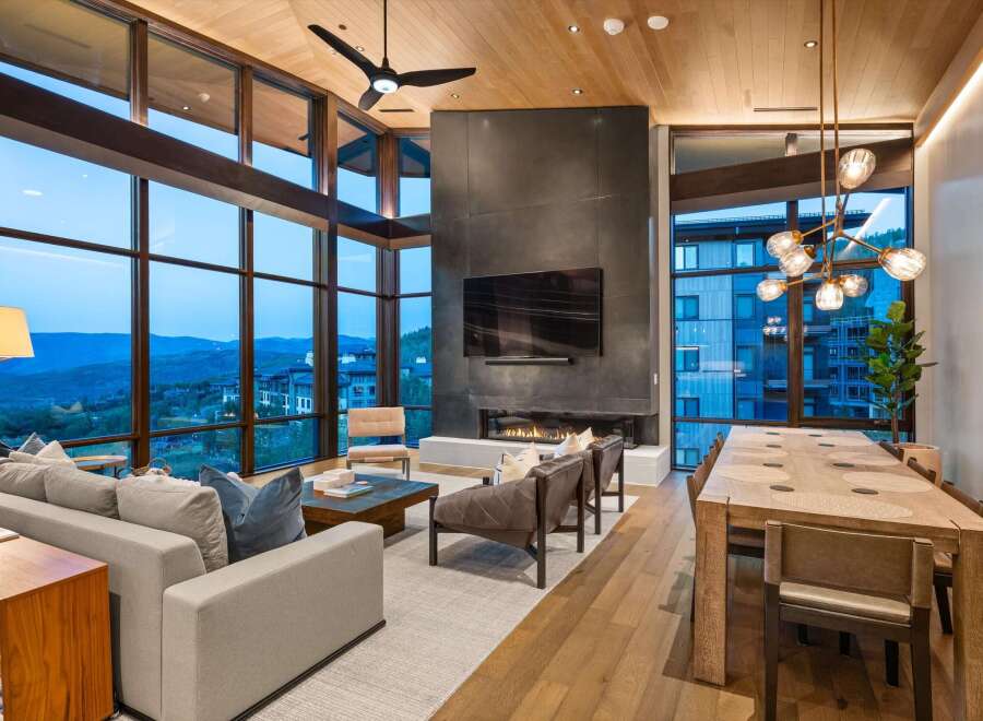 Experience luxury living with this stunning open-concept great room, featuring a dramatic floor-to-ceiling fireplace and expansive windows that frame breathtaking mountain views.