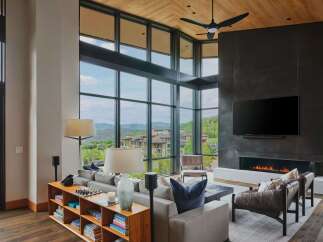 Experience luxury living in this stunning mountain view home, featuring a grand living room with a modern fireplace and expansive floor-to-ceiling windows.