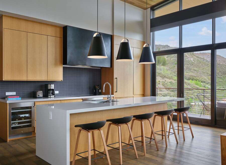 Experience modern luxury in this stunning kitchen, featuring sleek wood cabinetry, a spacious quartz island with bar seating, and a dramatic black range hood.