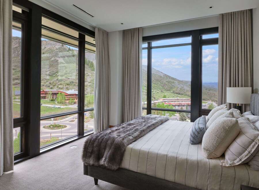 Experience luxury living with breathtaking mountain views from this stunning bedroom.