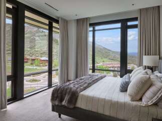 Experience luxury living with breathtaking mountain views from this stunning bedroom.