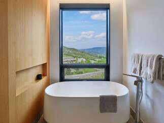 Experience ultimate relaxation in this luxurious bathroom featuring a freestanding soaking tub with a stunning mountain view.
