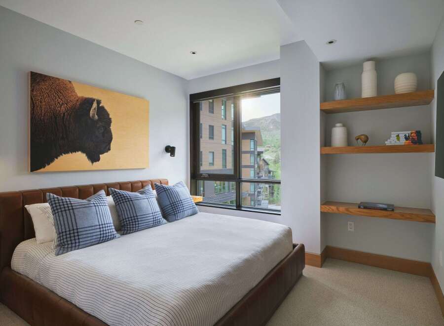Experience luxurious mountain living in this stunning bedroom, featuring a striking bison artwork above a plush leather bed.