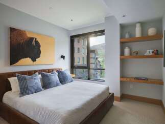 Experience luxurious mountain living in this stunning bedroom, featuring a striking bison artwork above a plush leather bed.