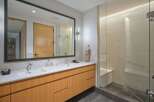 Experience modern luxury in this stunning bathroom featuring a spacious double vanity with sleek wood cabinetry and a large, illuminated mirror.