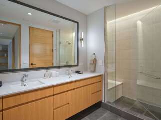 Experience modern luxury in this stunning bathroom featuring a spacious double vanity with sleek wood cabinetry and a large, illuminated mirror.