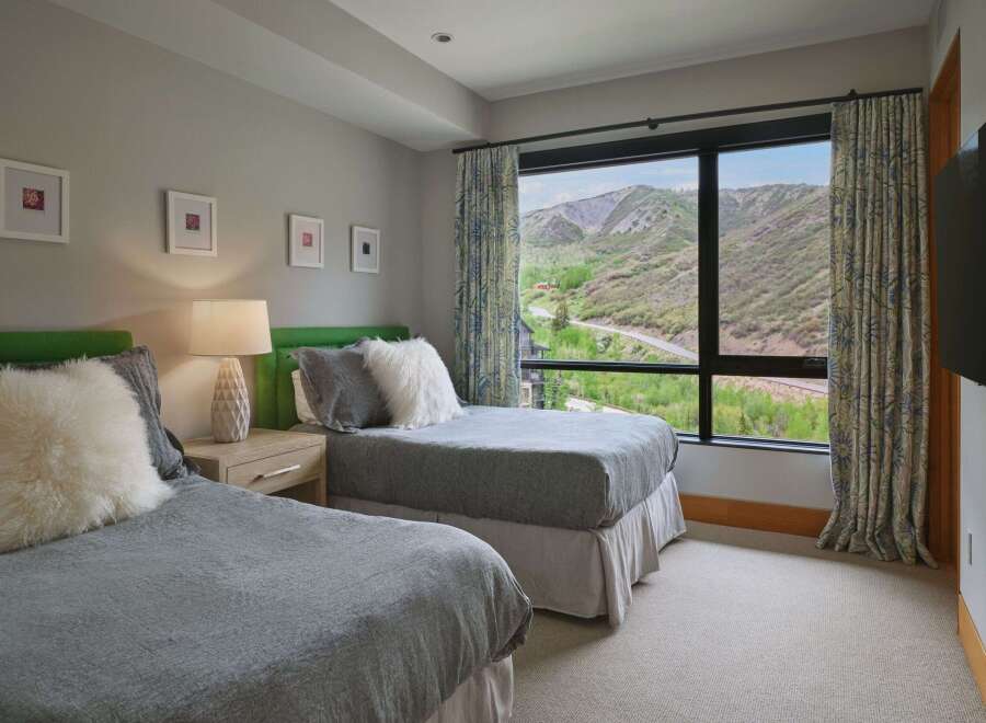 Experience breathtaking mountain views from this serene bedroom, featuring two comfortable beds perfect for family or guests.