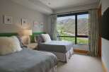 Experience breathtaking mountain views from this serene bedroom, featuring two comfortable beds perfect for family or guests.