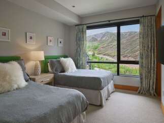 Experience breathtaking mountain views from this serene bedroom, featuring two comfortable beds perfect for family or guests.