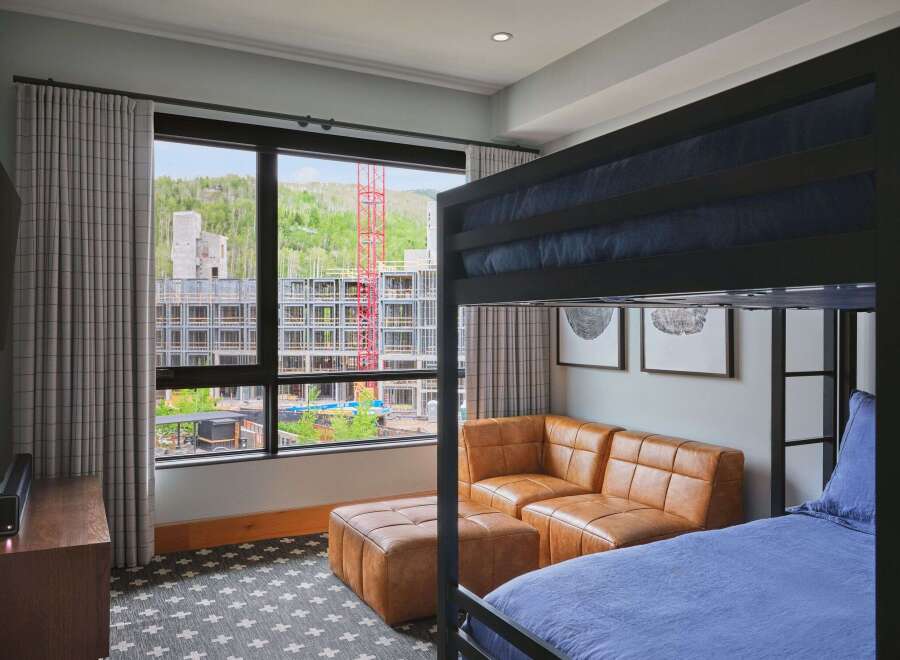 Experience modern comfort in this stylish room featuring a cozy bunk bed and a plush leather sectional sofa.
