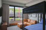 Experience modern comfort in this stylish room featuring a cozy bunk bed and a plush leather sectional sofa.