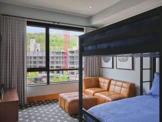 Experience modern comfort in this stylish room featuring a cozy bunk bed and a plush leather sectional sofa.