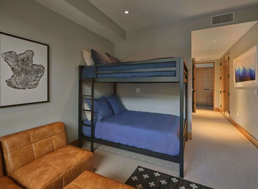 This cozy bedroom features a space-saving bunk bed with comfortable blue bedding, perfect for accommodating guests or children.