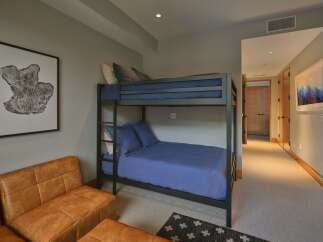 This cozy bedroom features a space-saving bunk bed with comfortable blue bedding, perfect for accommodating guests or children.
