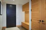Step into a modern entryway featuring a sleek black door and warm wood accents.
