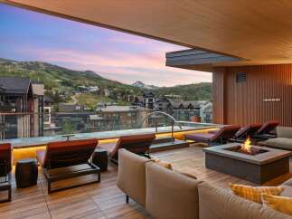 Experience luxury mountain living with this stunning rooftop deck, featuring a private hot tub and a cozy fire pit, perfect for enjoying breathtaking sunset views over the ski resort.