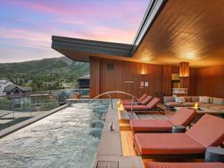 Experience luxury mountain living with this stunning rooftop spa featuring a relaxing hot tub and comfortable lounge area.