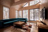 Experience serene winter living in this modern cabin featuring a spacious sectional sofa and a rustic wooden coffee table.
