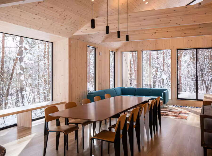 Experience the serene beauty of winter from this stunning dining area, featuring expansive windows that frame a snow-covered forest landscape.