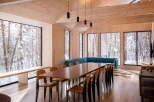 Experience the serene beauty of winter from this stunning dining area, featuring expansive windows that frame a snow-covered forest landscape.