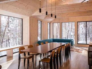 Experience the serene beauty of winter from this stunning dining area, featuring expansive windows that frame a snow-covered forest landscape.