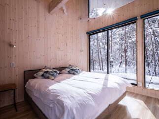Experience serene winter living in this cozy bedroom, featuring a comfortable bed adorned with stylish pillows.