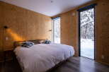 Experience cozy winter living in this unique bedroom, featuring rustic OSB walls and a comfortable bed.
