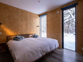 Experience cozy winter living in this unique bedroom, featuring rustic OSB walls and a comfortable bed.