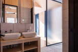 Experience modern luxury in this stunning bathroom featuring dual vessel sinks atop a sleek wooden vanity.