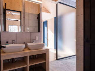 Experience modern luxury in this stunning bathroom featuring dual vessel sinks atop a sleek wooden vanity.