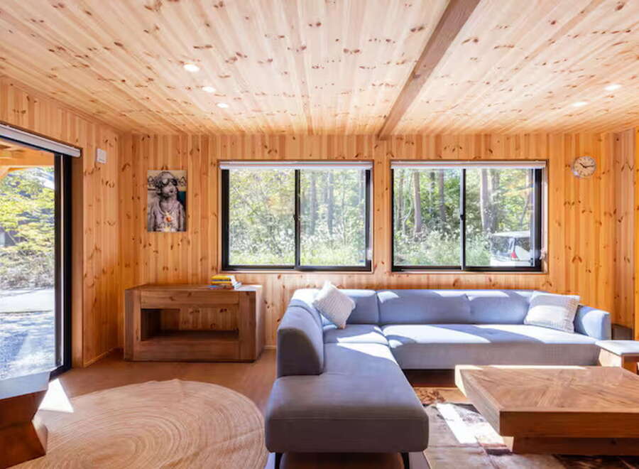 Experience serene living in this charming wooden cabin, featuring a spacious sectional sofa perfect for relaxation.