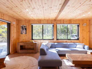 Experience serene living in this charming wooden cabin, featuring a spacious sectional sofa perfect for relaxation.