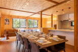 Experience the warmth of natural wood in this stunning dining area, featuring a long wooden table set for a feast.