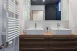 Experience modern luxury in this stunning bathroom featuring a sleek wooden vanity with dual vessel sinks and chrome fixtures.