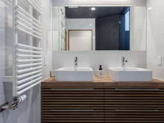 Experience modern luxury in this stunning bathroom featuring a sleek wooden vanity with dual vessel sinks and chrome fixtures.