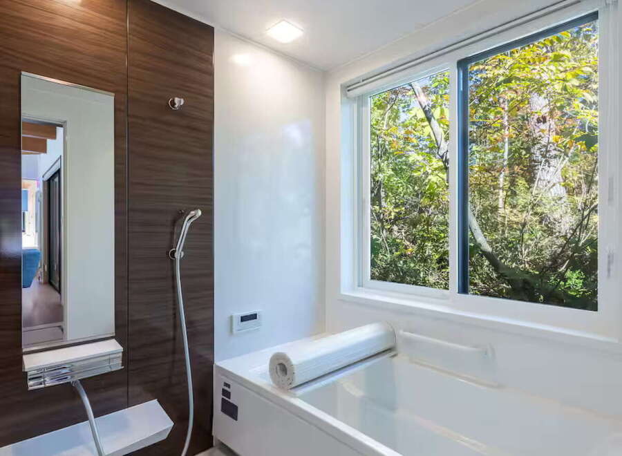 Experience ultimate relaxation in this modern bathroom featuring a deep soaking tub with a scenic forest view.