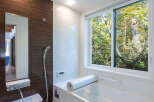 Experience ultimate relaxation in this modern bathroom featuring a deep soaking tub with a scenic forest view.