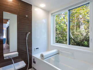 Experience ultimate relaxation in this modern bathroom featuring a deep soaking tub with a scenic forest view.