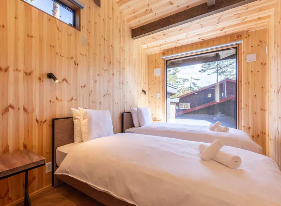 Experience cozy comfort in this charming wooden cabin bedroom, featuring two inviting twin beds dressed in crisp white linens.