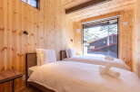 Experience cozy comfort in this charming wooden cabin bedroom, featuring two inviting twin beds dressed in crisp white linens.